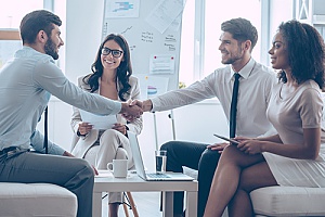 a small business owner shaking hands with his new employee after reaching an employment contract agreement