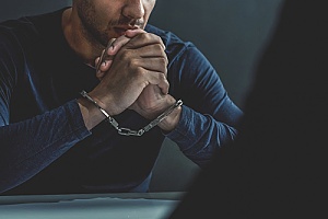 a man in handcuffs being interrogated by an investigator