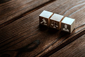 three small wooden blocks showing litigation symbols