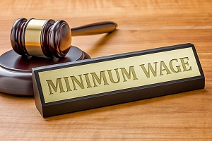 minimum wage placard with a judge gavel on a brown wooden table