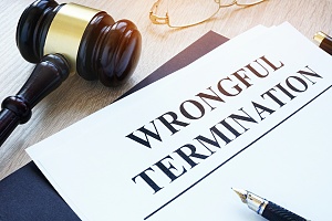 wrongful termination on a piece of paper with a judge gavel and a pen on table