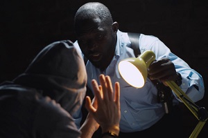 officer interrogating man suspected of crime glowing light of lamp into face