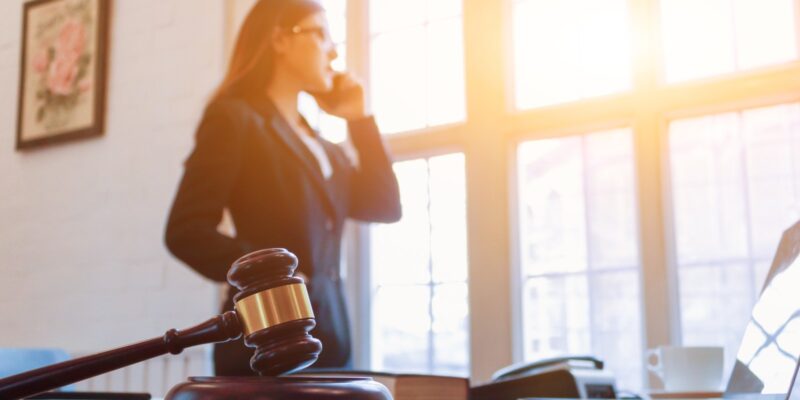 A female false arrest attorney is talking on the phone inside her office