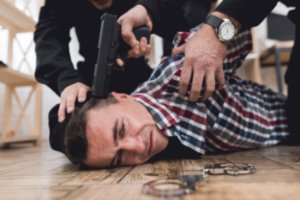 Gun on the head of the criminal resisting arrest by a police officer