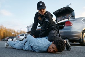 A female police officer tying the hands of a man resisting the arrest