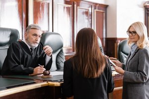 A female attorney representing her case against a male judge in the courtroom